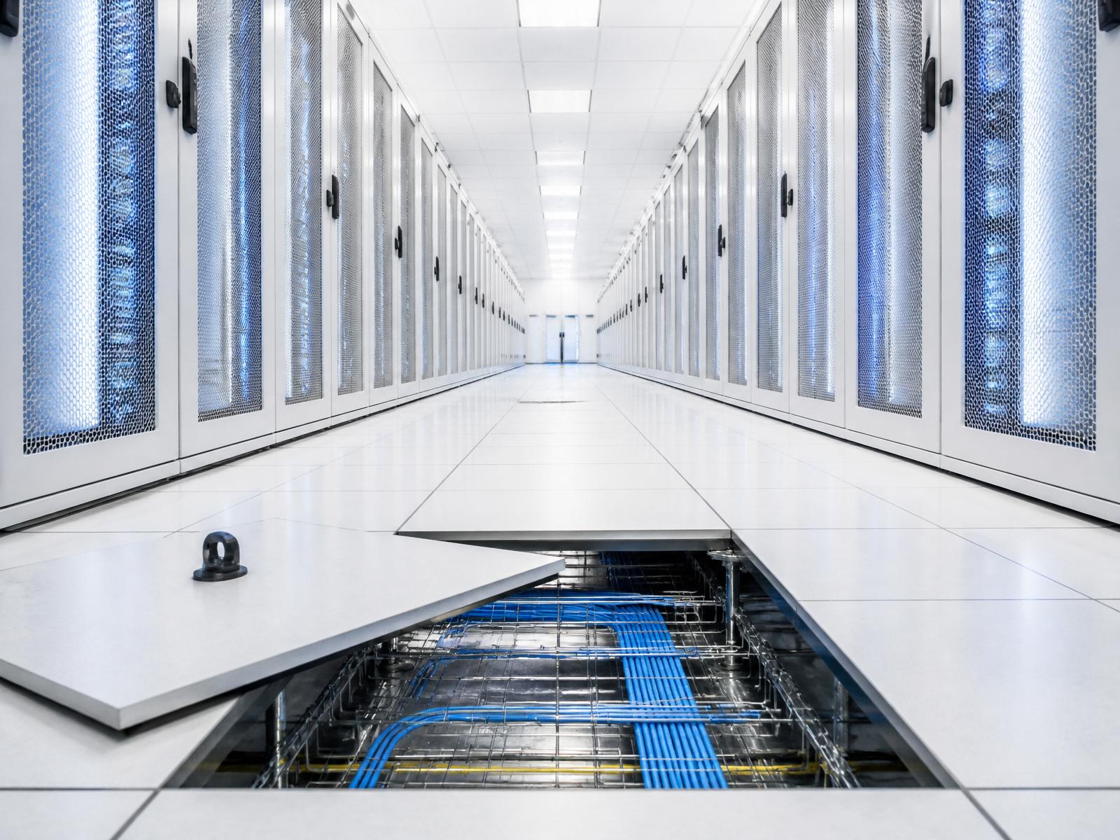 Pristine data hall aisle with a raised floor tile lifted, revealing an immaculately clean underfloor plenum.