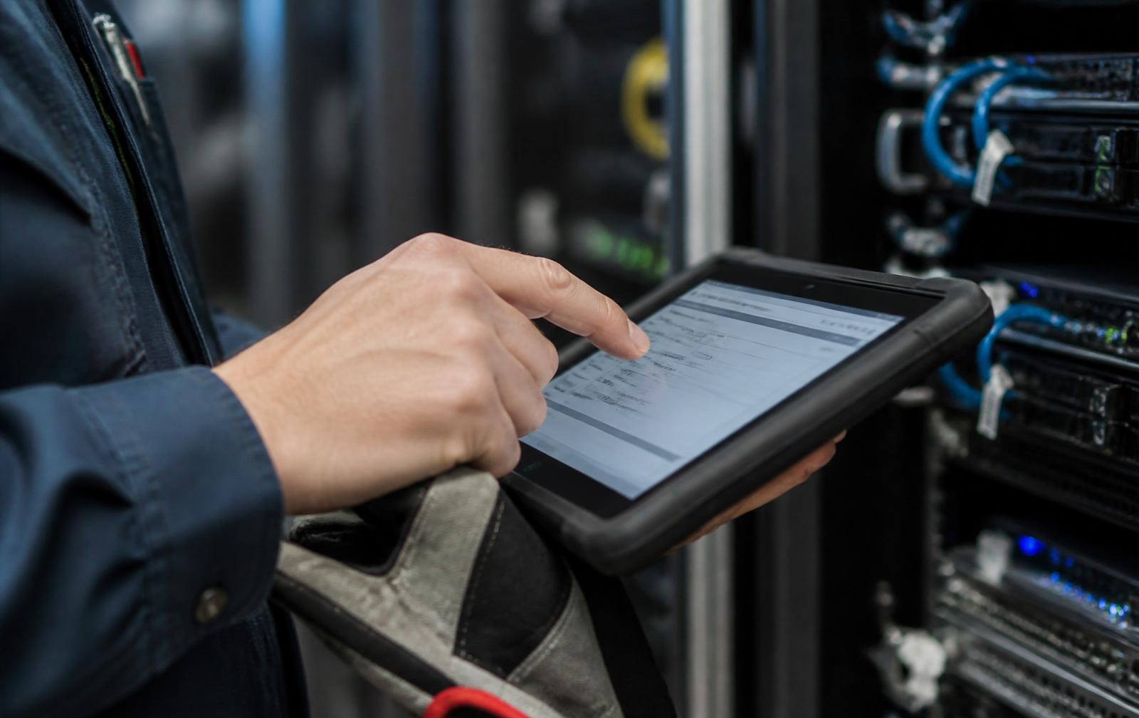 Technician documenting completed service on a rugged tablet in a data center.