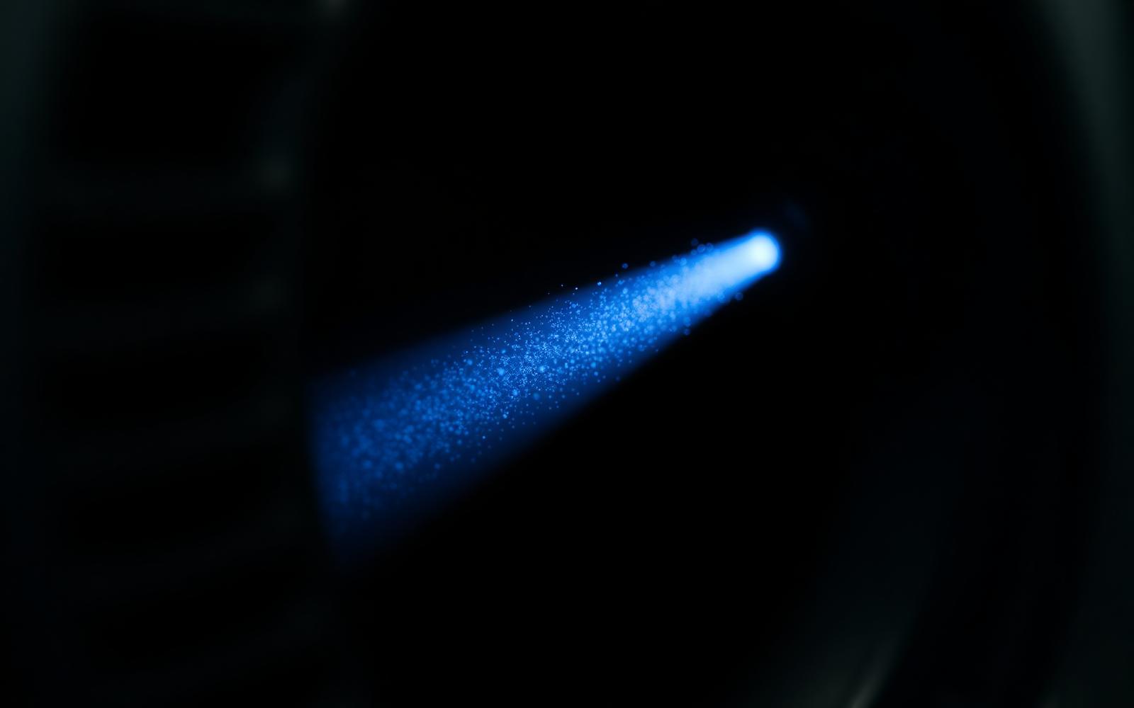 Fine particulate suspended in a shaft of blue light near a server intake.